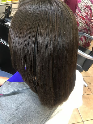 A person with sleek, smooth, and straight brown hair is seated in a salon chair