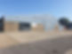 Industrial warehouse with blue corrugated metal exterior and parking area in sunny weather