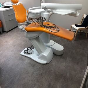 Orange dental chair in a clean, modern clinic with grey floors