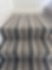 Close-up of a well-cleaned staircase featuring striped carpet