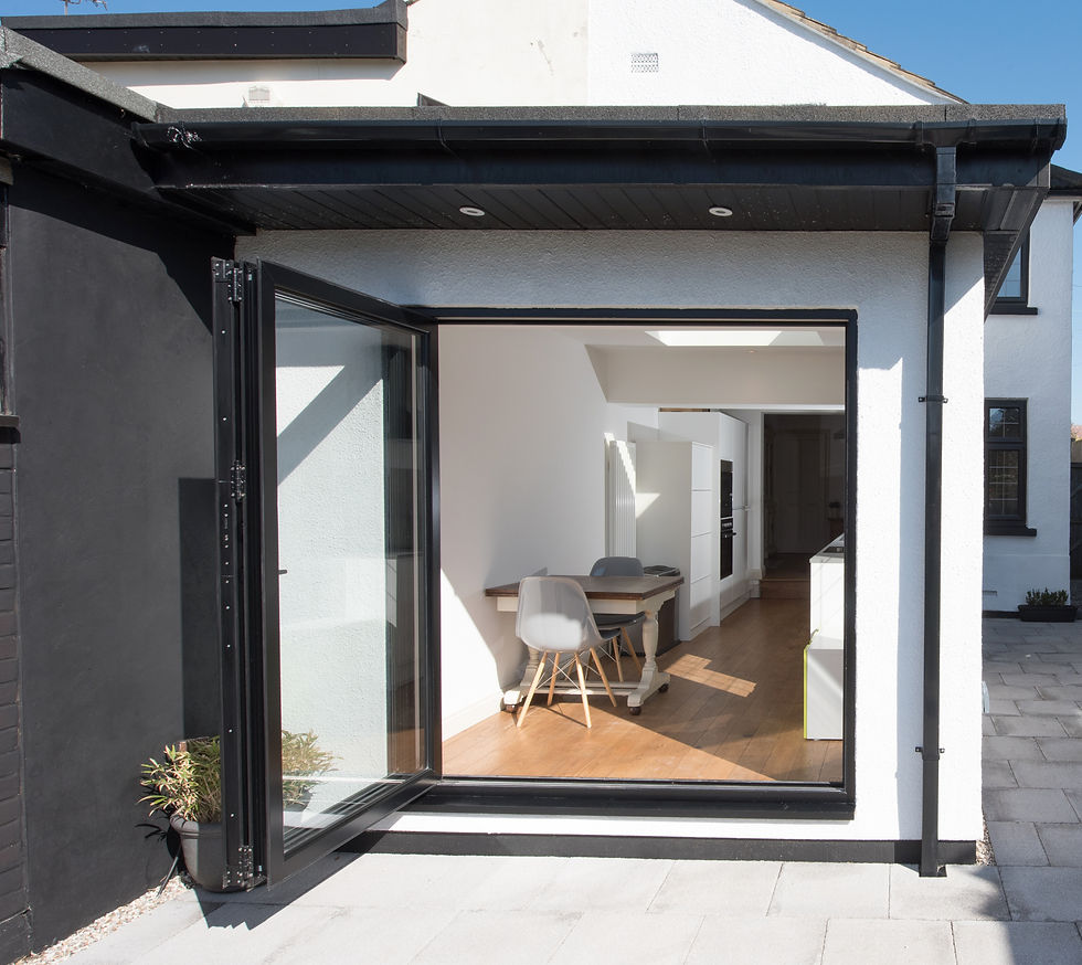 a modern home rear extension featuring black-framed bi-folding glass doors that open outward onto a paved patio