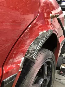 A red car with a scratched fender, showing a repair in progress