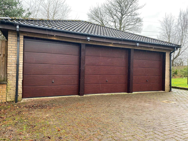 Three closed wooden garage doors in a row, featuring a rich brown finish