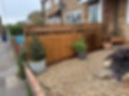 A robust newly fitted closeboard wooden boundary fence enclosing a gravel driveway