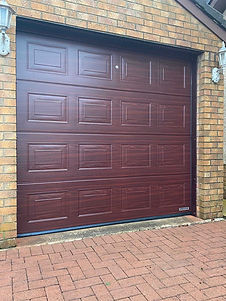 A brown, wooden-patterned garage door set in a brick wall