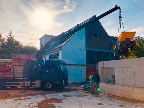 A crane lifting a concrete block onto a truck at a construction site