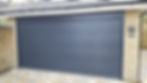 A modern, dark grey garage door with horizontal panels