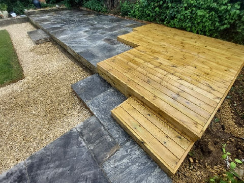 Wooden decking with stone steps surrounded by greenery