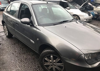 Front three quarter view of a grey sedan parked outside a workshop
