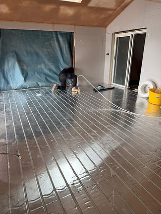 A worker installing metallic heat plates on an residential underfloor network