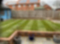 A garden featuring a green lawn bordered by a sturdy brick wall