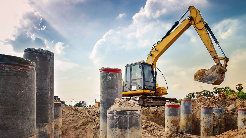 A large yellow excavator operating on a commercial site with concrete pillar foundations