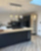 Modern kitchen featuring sleek black cabinetry, a wooden island, built-in appliances, and stylish pendant lighting