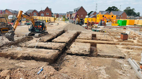 Construction site with heavy machinery digging trenches in the foreground