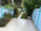A long narrow garden path flanked by lush green grass borders