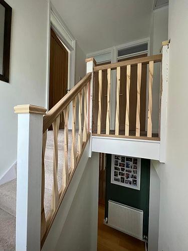 A wooden-railed staircase against a clean white wall