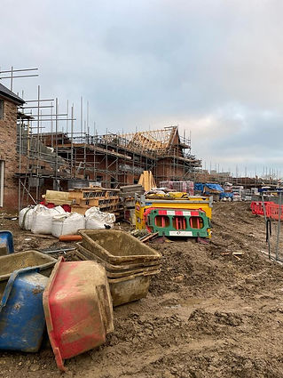 Construction site with unfinished buildings, scaffolding, construction materials, and muddy terrain