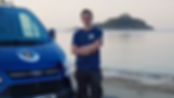 A person stands confidently next to a blue van