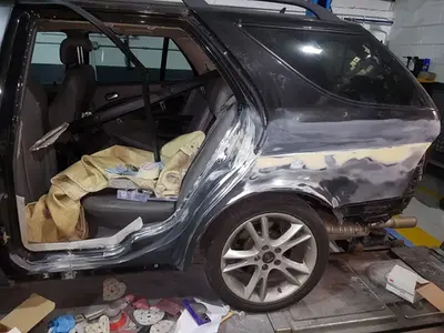 A black SUV is parked indoors undergoing bodywork repair