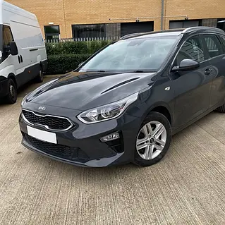 Dark grey car parked on a concrete forecourt