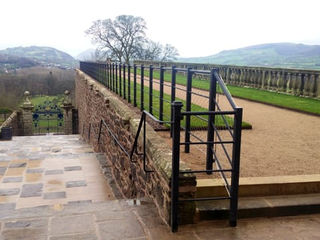 a stone wall with a fence and grass field