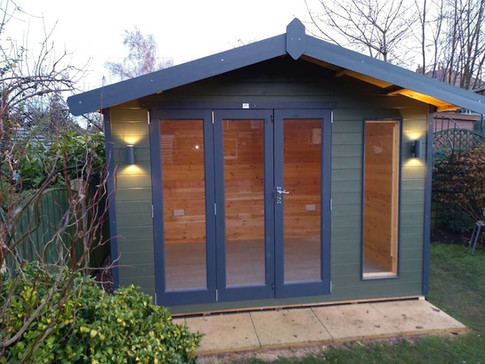 A small, modern garden shed with green walls