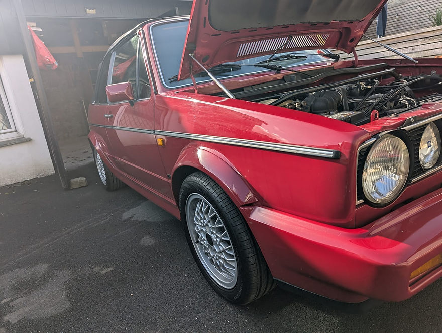 A red car with its hood open, revealing the engine compartment