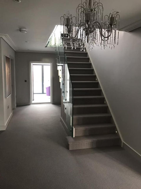 A grey carpeted hallway with a modern staircase
