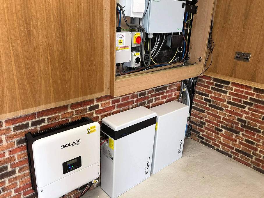 Multiple white battery storage modules aligned against an interior brick wall