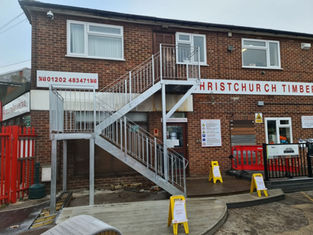 Exterior of a brick building with metal staircase and "Christchurch Timber" signage