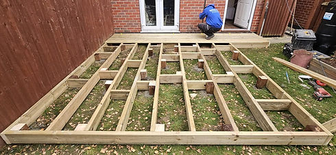 Wooden deck framework construction with a person working in the background