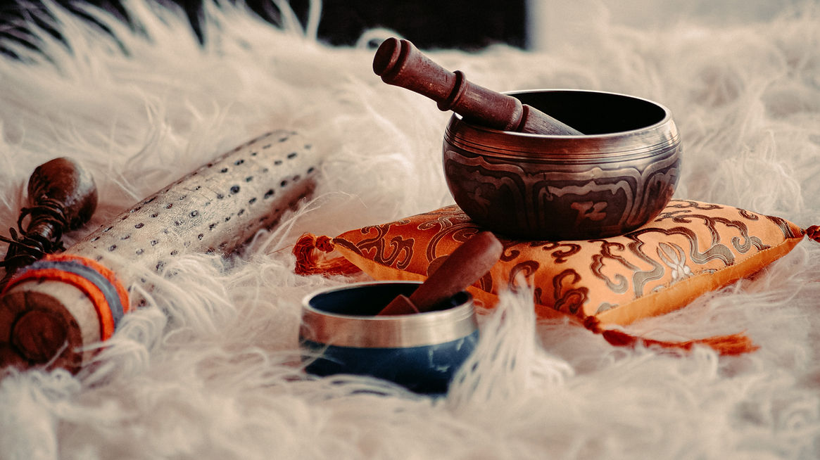 Singing bowls with mallets rest on a fluffy surface