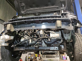 Underneath a car with the hood raised, showcasing the exposed engine components