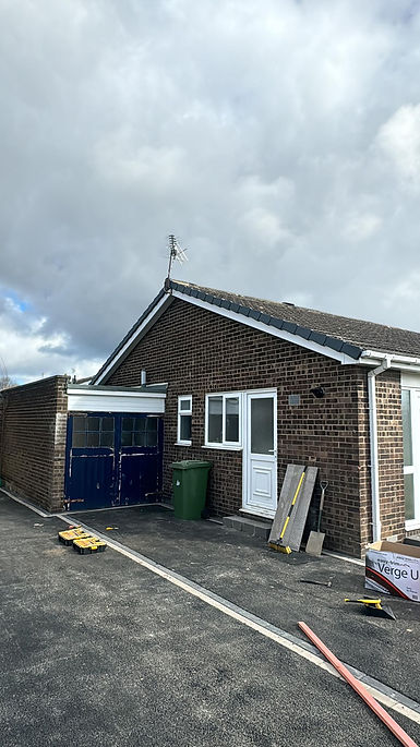 A brick bungalow with a dark tiled roof and blue garage doors