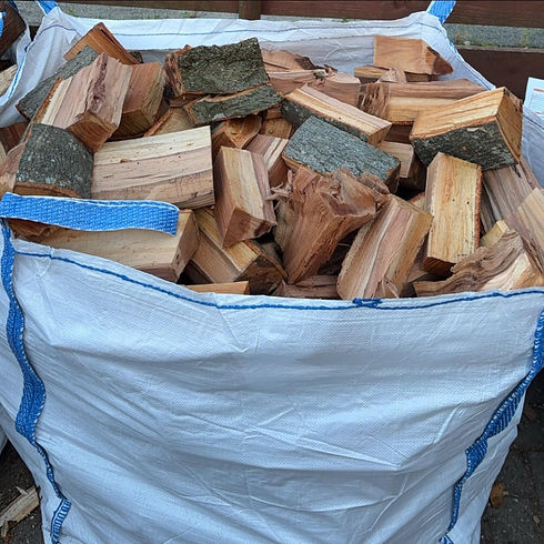 A large white bulk bag filled with seasoned hardwood logs