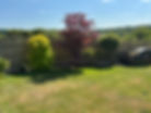 A sunlit open residential lawn lined with decorative timber fence borders