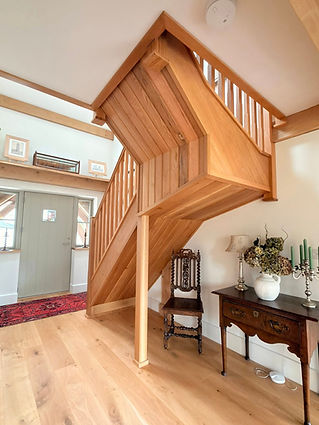 Impressive bespoke grand oak staircase turning upward in a spacious home hallway