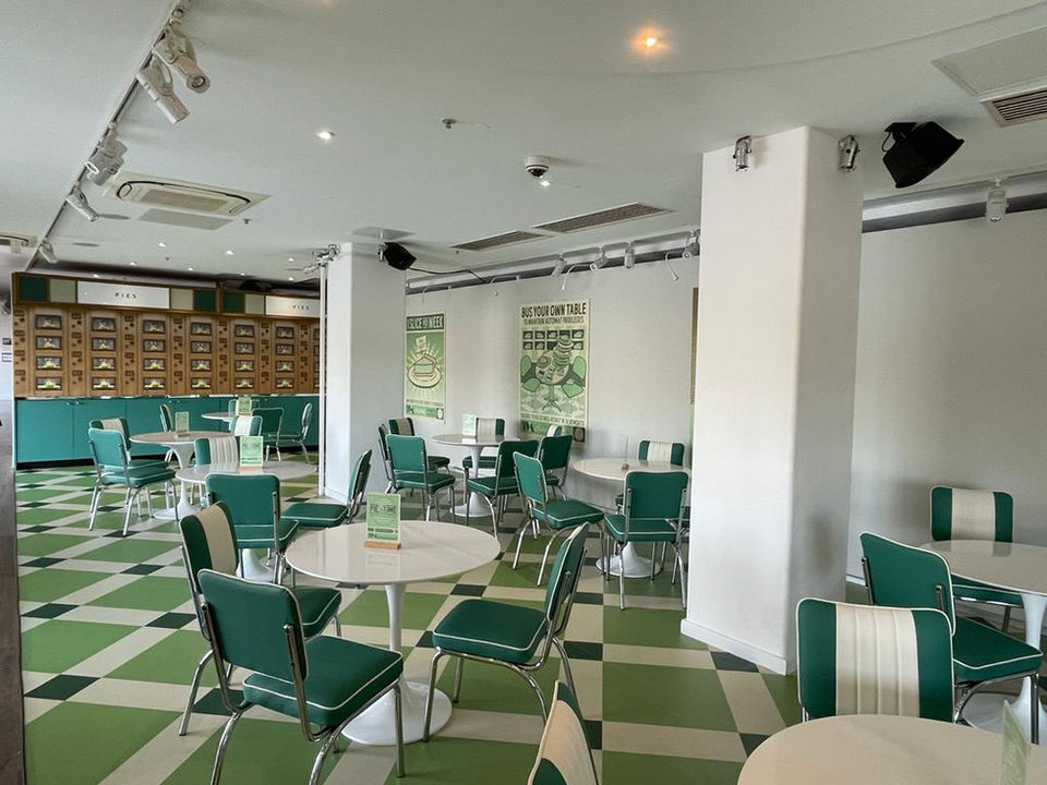 Retro-themed café with green and white checkered floors, green vinyl chairs, and round tables