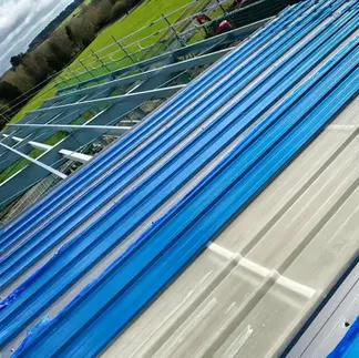 Construction view of a blue corrugated metal roof under installation
