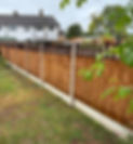 A long neat wooden perimeter fence bordering an open green field