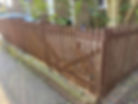 A long straight wooden panel fence enclosing a wide domestic backyard garden