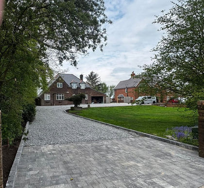 Long paved driveway running alongside a lawn toward a residential house