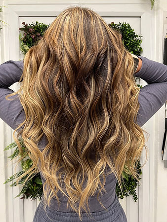 A close-up of the back of a woman's head showcasing her long, wavy hair