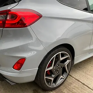 The rear side of a clean, light grey car