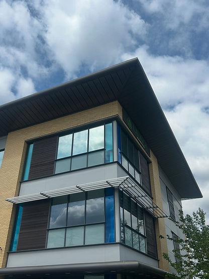 Modern building corner with large reflective windows contrasting against a partly cloudy sky