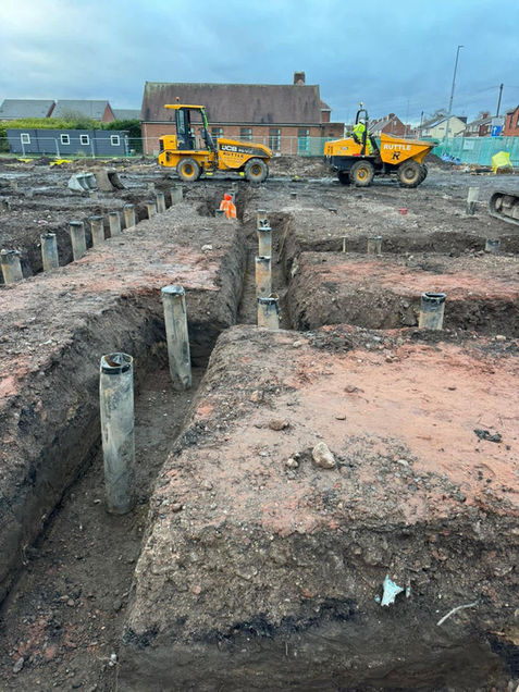 Construction site with exposed trenches, metal piles, and heavy machinery