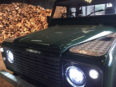 Close-up of an emerald green Land Rover Defender in a log factory