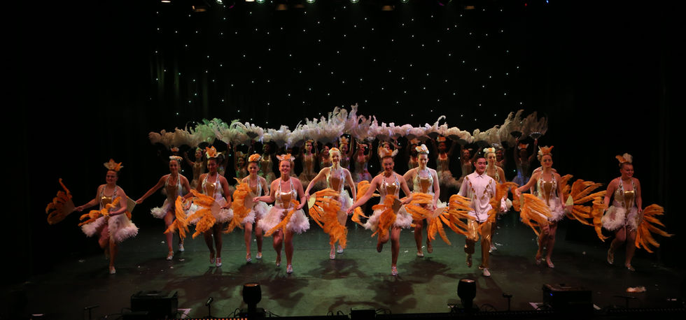 View of a group of children performing in orange and white costume
