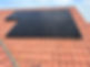 A close-up of a roof with terracotta tiles featuring sleek black solar panels installed on the surface
