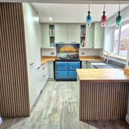 The kitchen features light cabinetry, wooden countertops, and colourful pendant lights